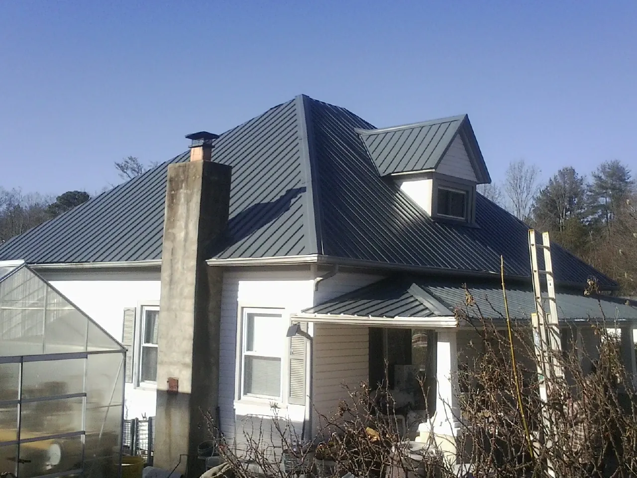 Dark blue standing seam metal roof on a white farmhouse with dormer — Slate & Tile Roof Repair by Roofing Brothers in New Tazewell