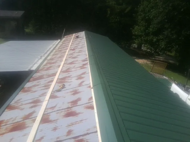 Old rusted panels beside newly installed green metal roofing — Wind Damage Roof Repair by Roofing Brothers in New Tazewell