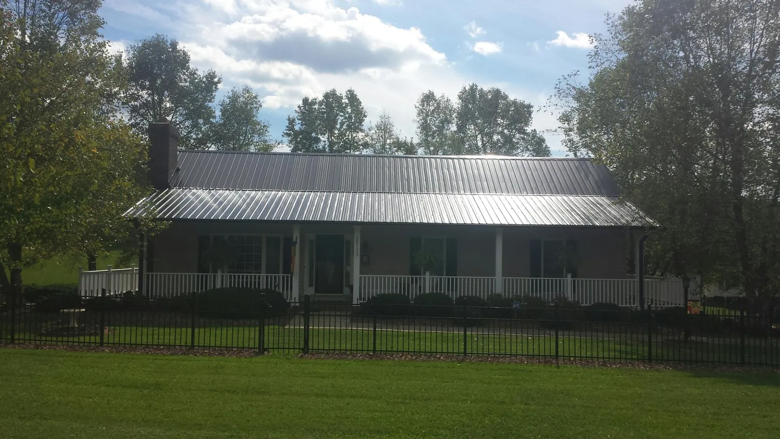 Gray metal roof on a brick ranch with a full width front porch — Gutter Guard Installation work by our crew in New Tazewell