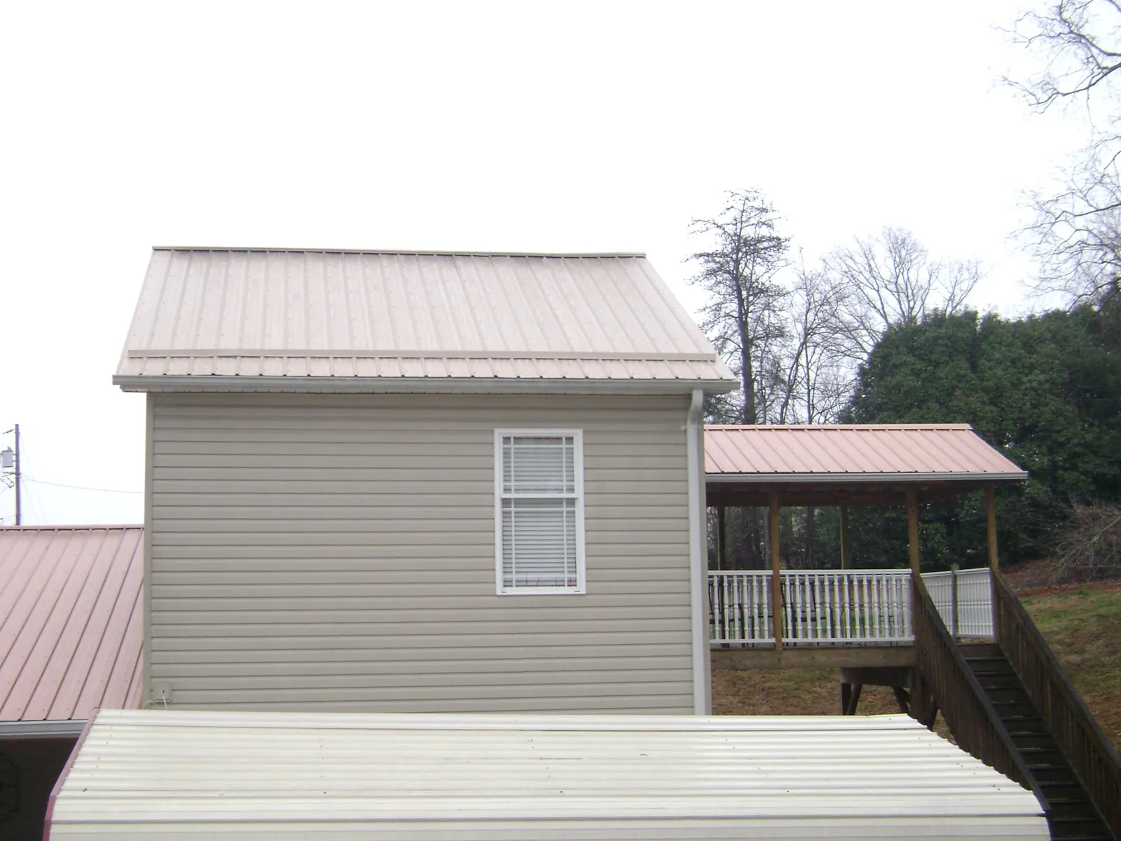 Tan metal roofs on a two story addition and attached porch, from a Roof Replacement job in New Tazewell